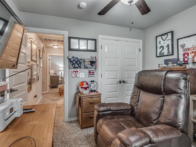sitting room with visible vents, light carpet, baseboards, attic access, and a ceiling fan