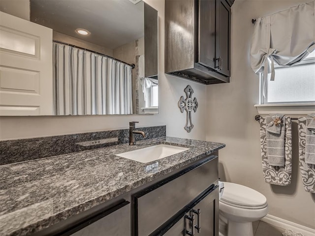 full bath with vanity, baseboards, plenty of natural light, and toilet