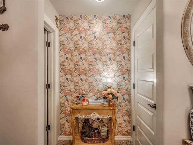 corridor featuring baseboards and wallpapered walls
