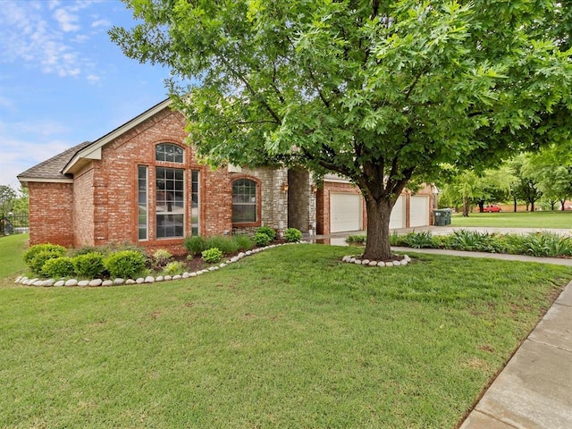 view of front of house featuring brick siding, a front yard, and driveway