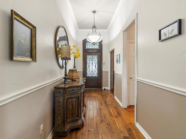 foyer entrance with hardwood / wood-style flooring, crown molding, and baseboards