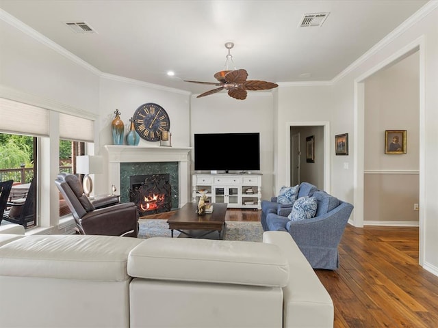 living room with ornamental molding, a fireplace, dark wood-type flooring, a ceiling fan, and baseboards