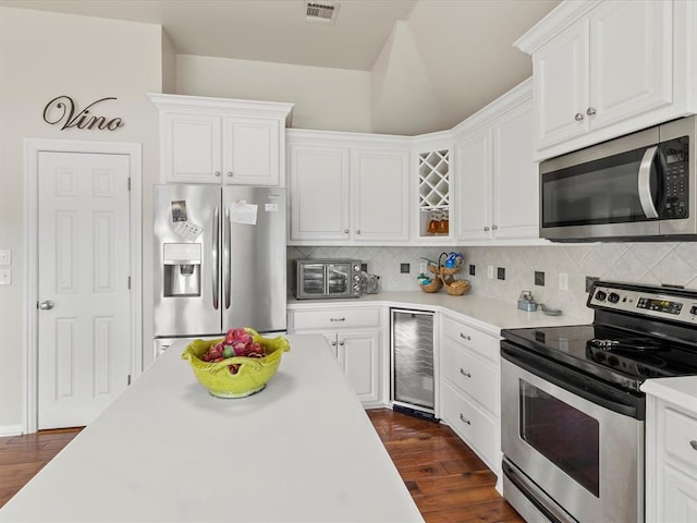kitchen with stainless steel appliances, wine cooler, white cabinets, light countertops, and backsplash