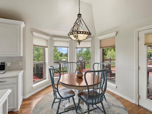 dining space featuring light wood finished floors, plenty of natural light, high vaulted ceiling, and baseboards