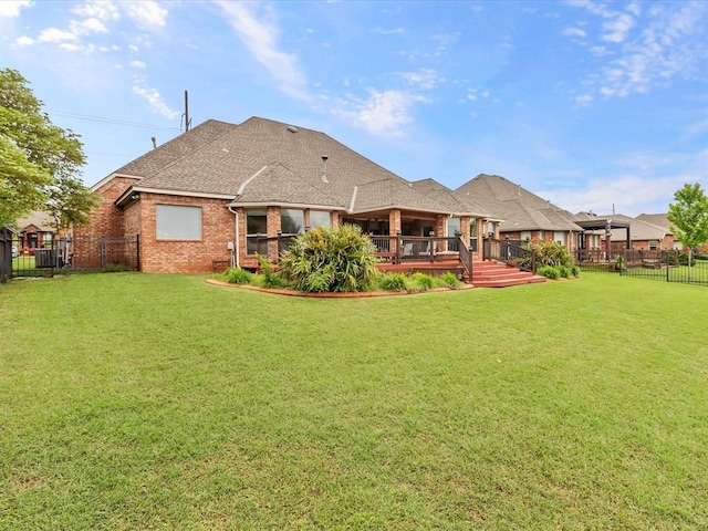 rear view of house with a deck, brick siding, and a shingled roof