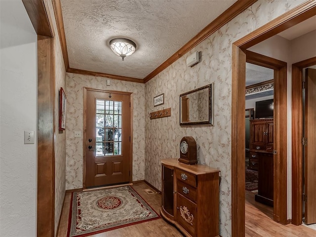 doorway to outside with baseboards, ornamental molding, light wood finished floors, and a textured ceiling