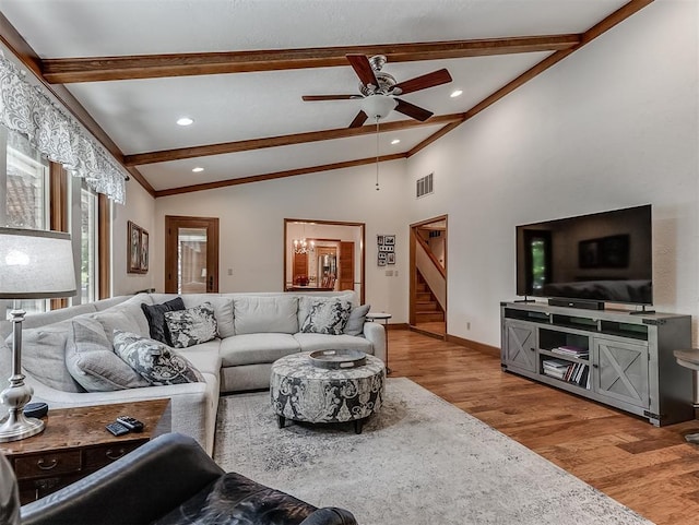 living area featuring a ceiling fan, visible vents, wood finished floors, vaulted ceiling with beams, and stairs