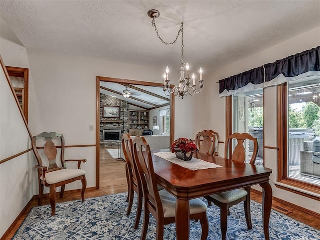 dining space with a notable chandelier, vaulted ceiling, plenty of natural light, and light wood finished floors