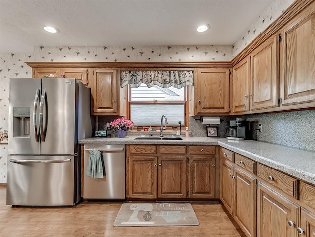 kitchen featuring a sink, light countertops, stainless steel appliances, and light wood-type flooring