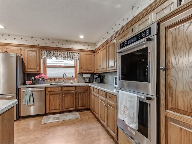kitchen featuring light wood-type flooring, a sink, decorative backsplash, and stainless steel appliances