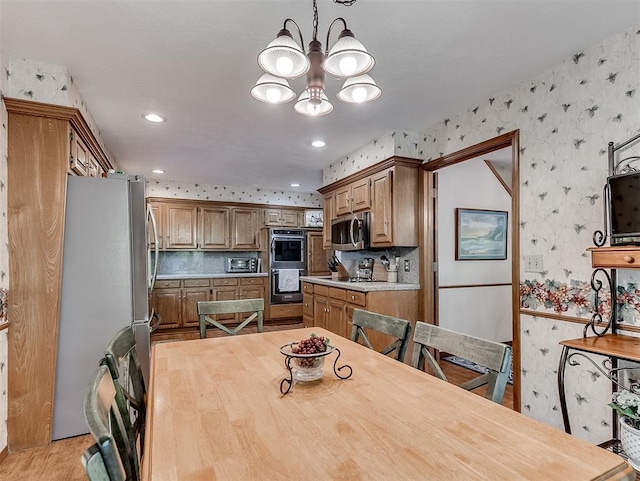 dining room with light wood-style floors, a chandelier, recessed lighting, wallpapered walls, and a toaster