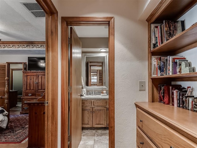 bathroom with vanity, a textured wall, and visible vents