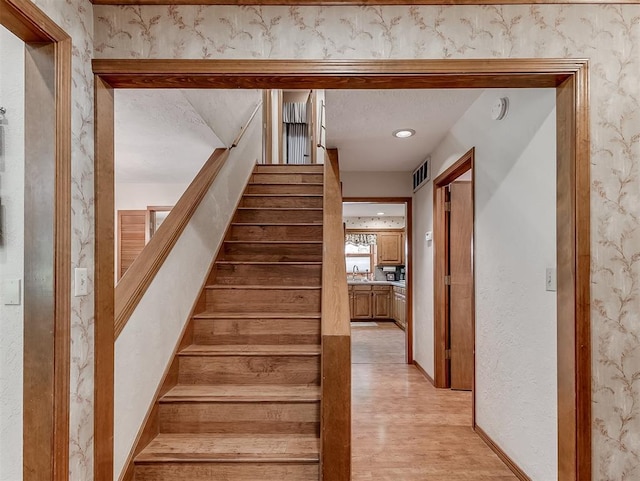 staircase featuring baseboards, visible vents, and wood finished floors