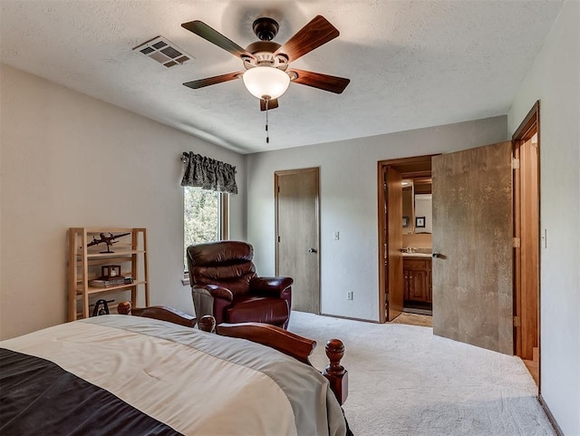 carpeted bedroom featuring visible vents, connected bathroom, a textured ceiling, and ceiling fan