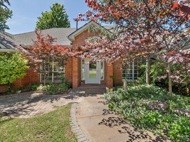 view of front of property with roof with shingles and brick siding