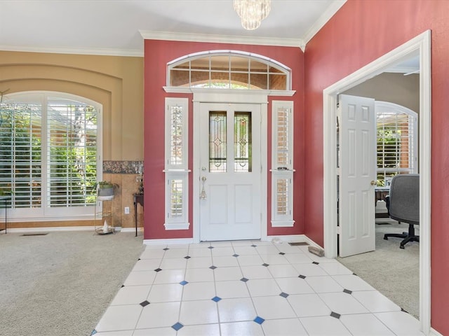 carpeted entrance foyer with baseboards, a chandelier, and ornamental molding