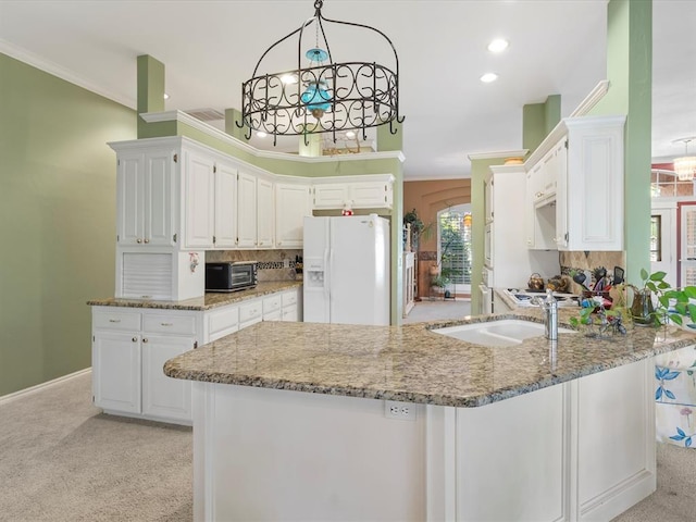 kitchen with light stone counters, white refrigerator with ice dispenser, a peninsula, and light colored carpet