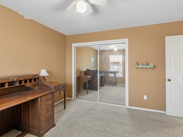 office space featuring baseboards, ceiling fan, and light colored carpet