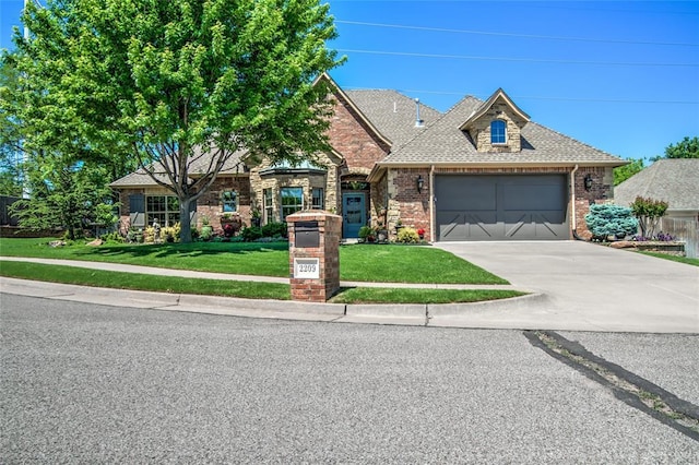 view of front of property featuring brick siding, an attached garage, driveway, and a front yard