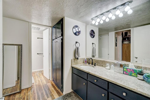 6000 N Pennsylvania Ave Unit 59, Oklahoma City, OK 73112 - bathroom featuring vanity, visible vents, wood finished floors, baseboards, and a textured ceiling
