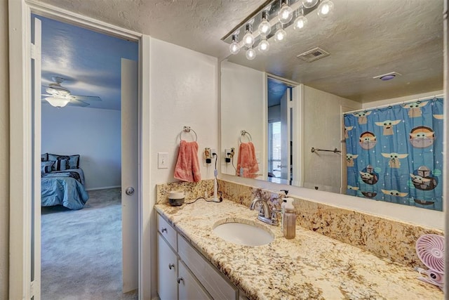6000 N Pennsylvania Ave Unit 59, Oklahoma City, OK 73112 - bathroom featuring visible vents, vanity, baseboards, ceiling fan, and a textured ceiling
