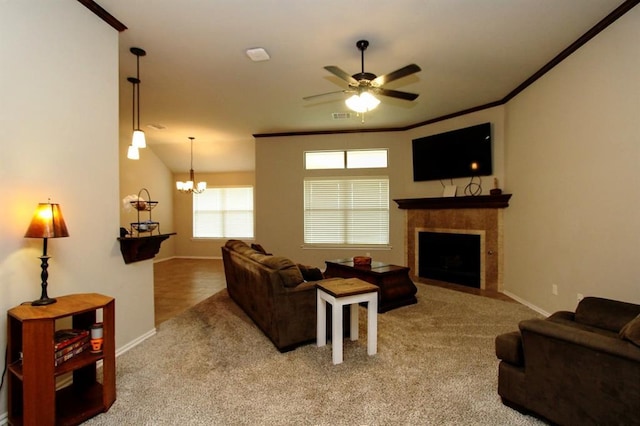 carpeted living room featuring baseboards, ceiling fan, a chandelier, a fireplace, and crown molding