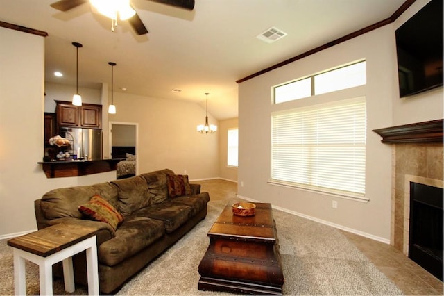 living room with a ceiling fan, baseboards, a chandelier, a tiled fireplace, and carpet flooring