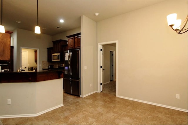 kitchen with freestanding refrigerator, stainless steel microwave, dark countertops, hanging light fixtures, and baseboards
