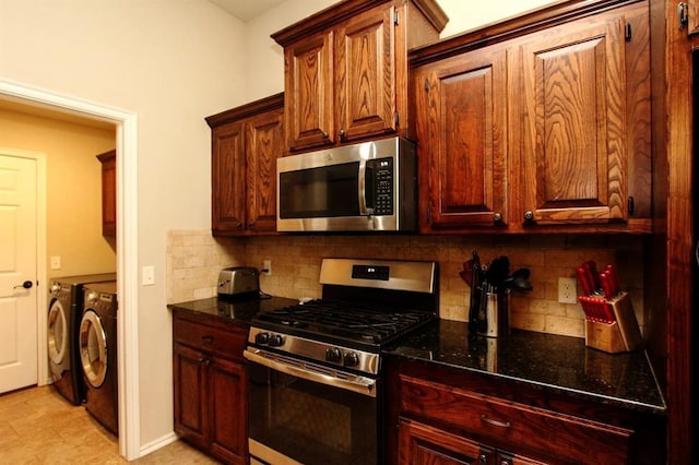 kitchen featuring stainless steel appliances, washing machine and dryer, dark stone countertops, and tasteful backsplash