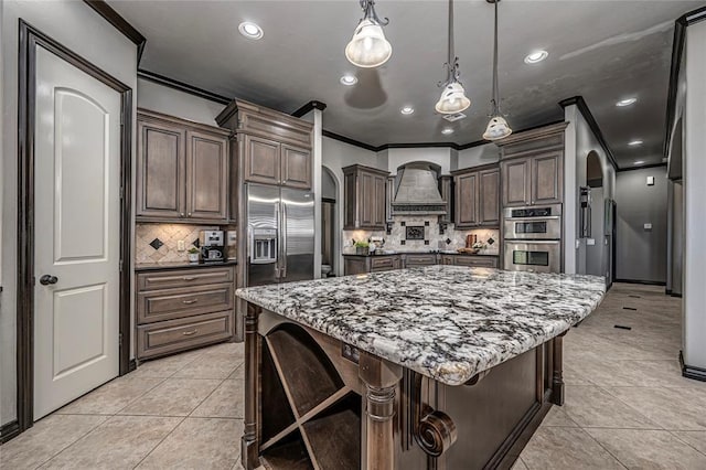 8521 NW 124th St, Oklahoma City, OK 73142 - kitchen featuring premium range hood, stainless steel appliances, arched walkways, ornamental molding, and light tile patterned flooring