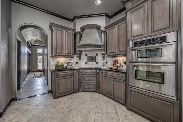 8521 NW 124th St, Oklahoma City, OK 73142 - kitchen featuring double oven, crown molding, dark countertops, decorative backsplash, and custom range hood