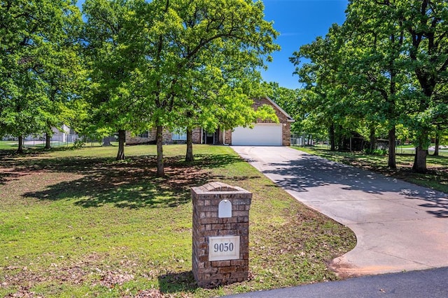 obstructed view of property featuring a garage, driveway, and a front lawn