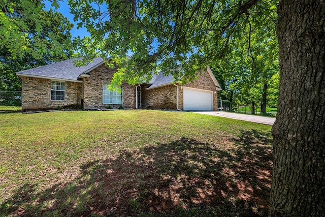 ranch-style home featuring fence, a front yard, roof with shingles, an attached garage, and driveway