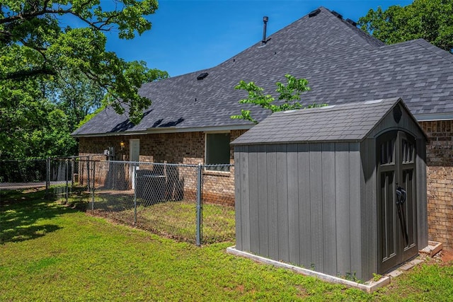 back of property featuring a lawn, fence, an outbuilding, and a storage unit