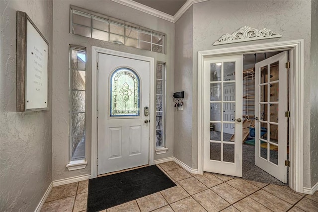 entrance foyer with french doors, ornamental molding, a textured wall, and baseboards