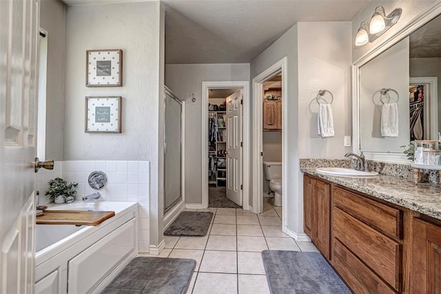 full bath with a walk in closet, tile patterned flooring, a shower stall, and toilet