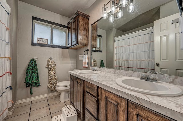 bathroom featuring toilet, baseboards, a sink, and tile patterned flooring
