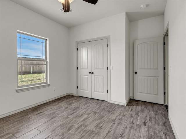 unfurnished bedroom featuring baseboards, ceiling fan, a closet, and light wood-type flooring