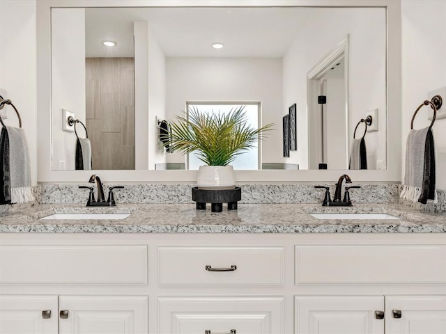 bathroom with double vanity, a sink, and recessed lighting