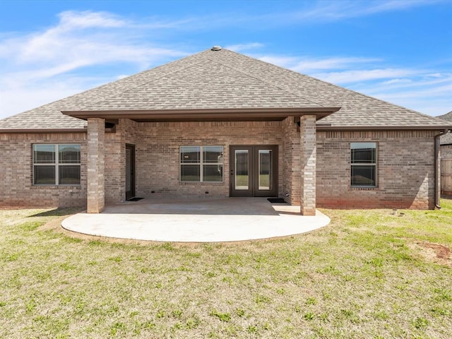 back of house featuring french doors, brick siding, a yard, and a shingled roof