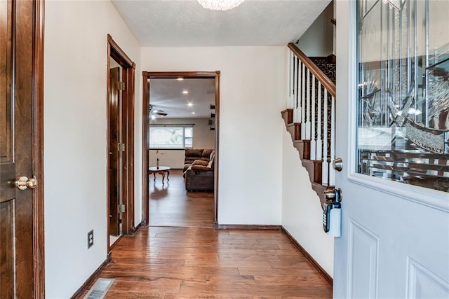 entryway with stairway, baseboards, wood finished floors, and visible vents