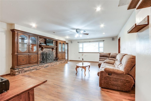 living area with light wood-style floors, a brick fireplace, a ceiling fan, baseboards, and recessed lighting