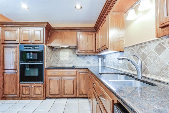 kitchen with a sink, brown cabinetry, dark stone counters, tasteful backsplash, and black appliances