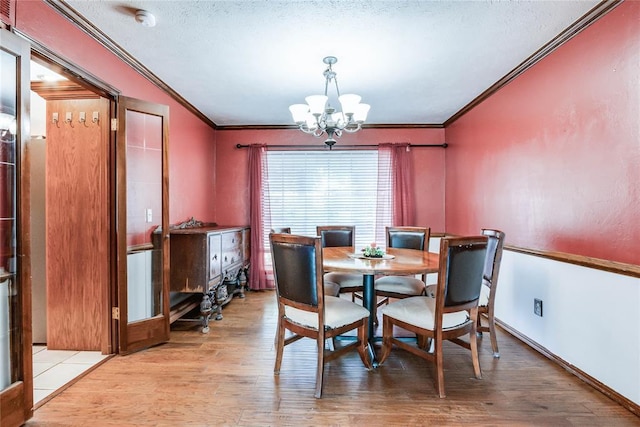 dining space featuring a textured ceiling, a chandelier, ornamental molding, and wood finished floors