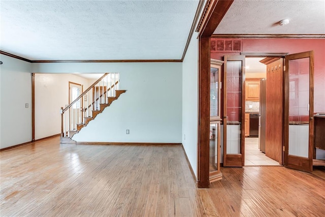 unfurnished room with light wood-style floors, ornamental molding, a textured ceiling, and stairway