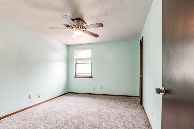 carpeted empty room with a textured ceiling, ceiling fan, and baseboards