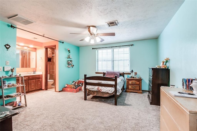bedroom featuring light colored carpet, a textured ceiling, and visible vents