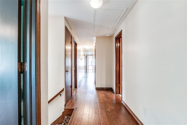 hall with an upstairs landing, attic access, and dark wood-type flooring