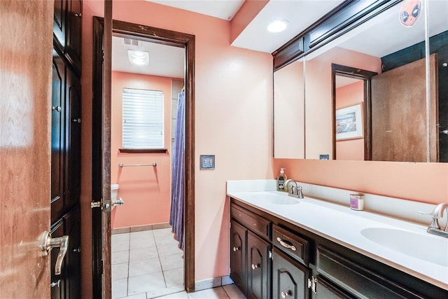 bathroom featuring a sink, baseboards, tile patterned flooring, and double vanity