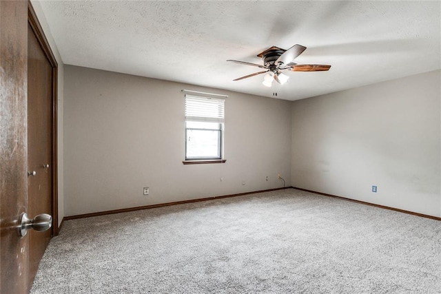 carpeted spare room featuring a textured ceiling, ceiling fan, and baseboards